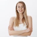 Confident and ambitious woman dreaming become director of company ready to work hard and determined holding hands crossed on chest in self-assured pose, smiling assertive over gray wall. Copy space