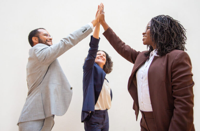 Happy business colleagues enjoying team success. Diverse group of man and women standing over white background and giving high five to each other. Achievement concept